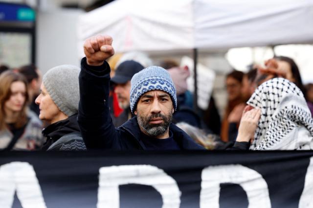 A protester raises his fist during a march to demand justice for El Hacen Diarra, who died in January in police custody at a police station, in Paris on February 21, 2026. The 35-year-old Mauritanian man died during the night of January 15-16 while in police custody at the 20th arrondissement police station in Paris, after being arrested outside his workers' hostel. His family has denounced police violence, and a video shot by a neighbor shows two police officers, one of whom is kneeling and punching the man on the ground twice. (Photo by Charlotte SIEMON / AFP)
