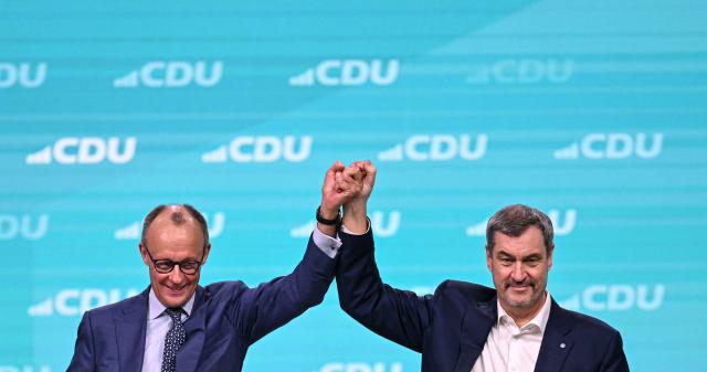 Germany's Chancellor Friedrich Merz and Bavaria's State Premier and leader of the conservative Christian Social Union (CSU) Markus Soeder react on stage during the party congress of Germany's Christian Democratic Union (CDU) in Stuttgart, southern Germany, on February 21, 2026. (Photo by THOMAS KIENZLE / AFP)