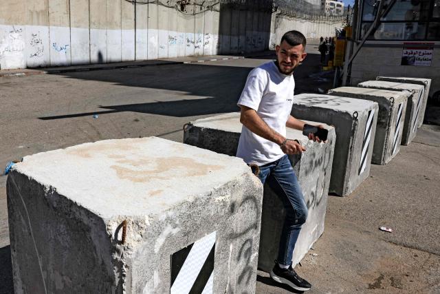 A man walks past concrete barrier blocks installed by Israeli police the prior week alongside Israel's controversial separation barrier in Israeli-annexed east Jerusalem across from Beit Hanina on February 21, 2026. (Photo by AHMAD GHARABLI / AFP)