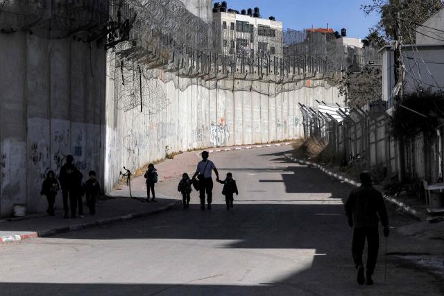 Children walk alongside Israel's controversial separation barrier in Israeli-annexed east Jerusalem across from Beit Hanina on February 21, 2026. (Photo by AHMAD GHARABLI / AFP)