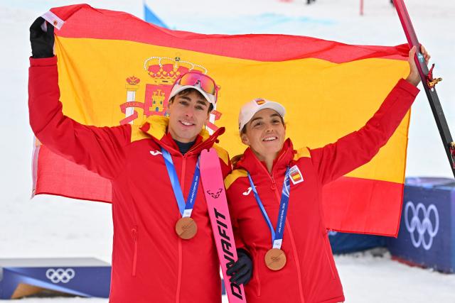 Bronze medallists Spain's Oriol Cardona Coll and Spain's Ana Alonso Rodriguez celebrate on the podium after competing in the mixed relay ski mountaineering event during the Milano Cortina 2026 Winter Olympic Games at the Stelvio Ski Centre in Bormio (Valtellina) on February 21, 2026. (Photo by Fabrice COFFRINI / AFP)