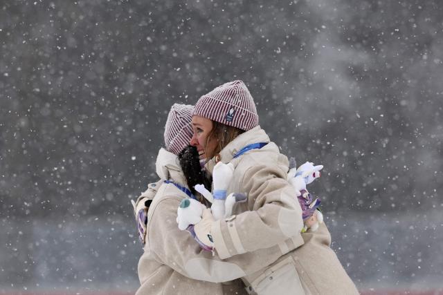 Silver medallist France's Julia Simon (L) hugs gold medallist France's Oceane Michelon on the podium of the women's biathlon 12.5km mass start event during the Milano Cortina 2026 Winter Olympic Games at the Anterselva Biathlon Arena (Sudtirol Arena) in Anterselva (Val Pusteria) on February 21, 2026. (Photo by FRANCK FIFE / AFP)