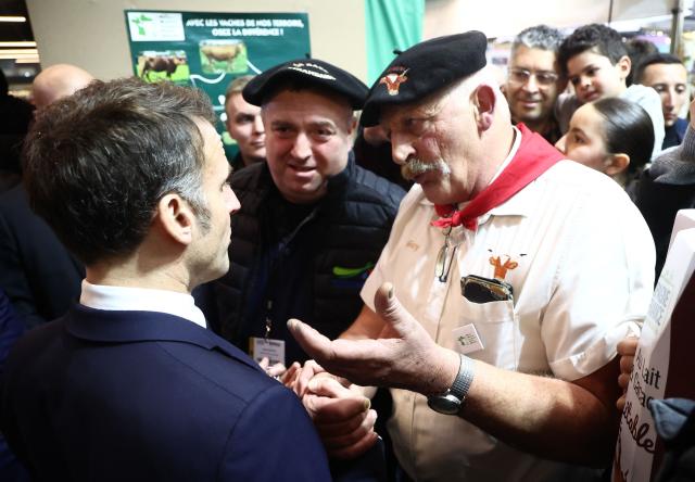 French President Emmanuel Macron (L) chats with breeders from southern France during the opening day of the International Agricultural Show (Salon de l'Agriculture) at Paris Expo Porte de Versailles in Paris on February 21, 2026. (Photo by Christophe PETIT TESSON / POOL / AFP)