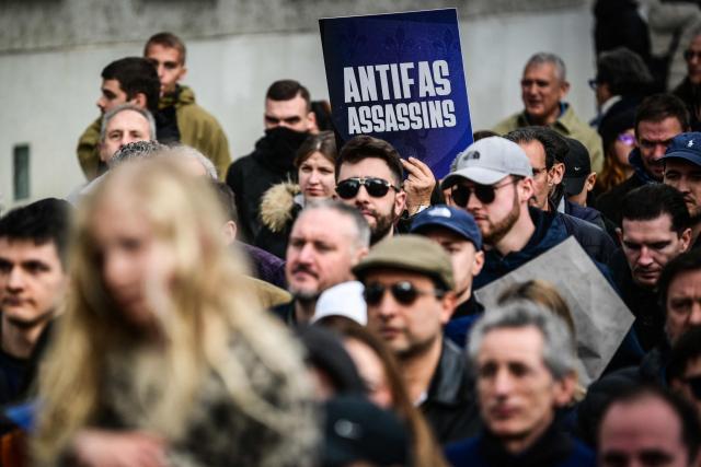 A protester hold a placard reading "Antifa murderers" during a march in tribute to far-right activist Quentin Deranque, who died after being attacked on the sidelines of a far-right protest against a La France Insoumise (LFI) event at Sciences Po Lyon, in Lyon on February 21, 2026. (Photo by OLIVIER CHASSIGNOLE / AFP)