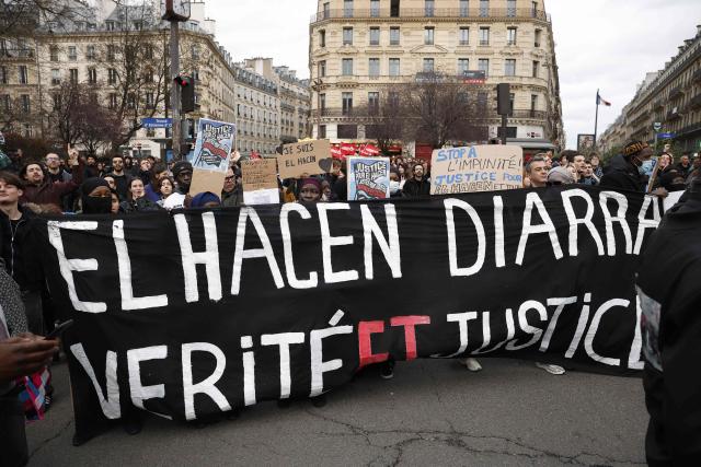 Protesters hold a banner during a march to demand justice for El Hacen Diarra, who died in January in police custody at a police station, in Paris on February 21, 2026. The 35-year-old Mauritanian man died during the night of January 15-16 while in police custody at the 20th arrondissement police station in Paris, after being arrested outside his workers' hostel. His family has denounced police violence, and a video shot by a neighbor shows two police officers, one of whom is kneeling and punching the man on the ground twice. (Photo by Charlotte SIEMON / AFP)