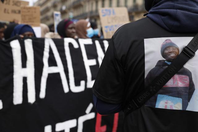 Protesters hold a banner during a march to demand justice for El Hacen Diarra (portrait), who died in January in police custody at a police station, in Paris on February 21, 2026. The 35-year-old Mauritanian man died during the night of January 15-16 while in police custody at the 20th arrondissement police station in Paris, after being arrested outside his workers' hostel. His family has denounced police violence, and a video shot by a neighbor shows two police officers, one of whom is kneeling and punching the man on the ground twice. (Photo by Charlotte SIEMON / AFP)