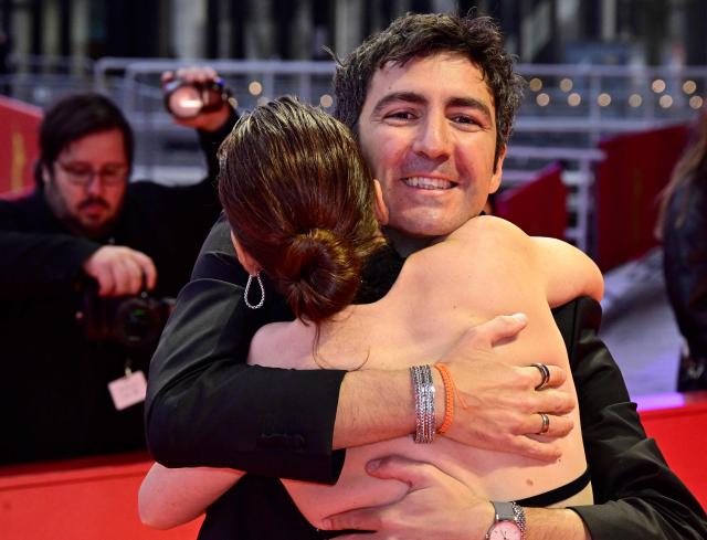 German director Ilker Catak is hugged by an unidentified woman as the crew of the movie "Gelbe Briefe" (Yellow Letters) arrives on the red carpet for the Award Ceremony of the 76th Berlinale, Europe's first major film festival of the year, in Berlin on February 21, 2026. The 76th Berlin Film Festival draws to a close after 10 days, with 22 films in competition. (Photo by John MACDOUGALL / AFP)