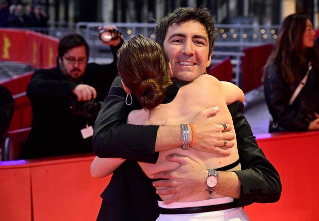 German director Ilker Catak is hugged by an unidentified woman as the crew of the movie "Gelbe Briefe" (Yellow Letters) arrives on the red carpet for the Award Ceremony of the 76th Berlinale, Europe's first major film festival of the year, in Berlin on February 21, 2026. The 76th Berlin Film Festival draws to a close after 10 days, with 22 films in competition. (Photo by John MACDOUGALL / AFP)