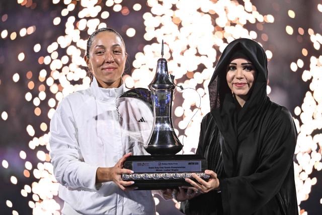 US' Jessica Pegula (L) celebrates with the trophy after winning her women’s singles final match against Ukraine's Elina Svitolina at the Dubai Duty Free Tennis tournament in Dubai on February 21, 2026. (Photo by Ryan Lim / AFP)