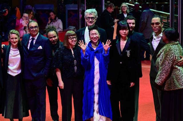 Jury President, German director Wim Wenders (C) poses with Berlinale director Tricia Tuttle and the members of the jury, (L-R) Indian director Shivendra Singh Dungarpuras, Nepalese filmmaker Min Bahadur Bham, Polish producer Ewa Puszczynska,  Japanese director Hikari, South Korean actress Bae Doona, and US director Reinaldo Marcus Green as they arrive on the red carpet for the Award Ceremony of the 76th Berlinale, Europe's first major film festival of the year, in Berlin on February 21, 2026. (Photo by John MACDOUGALL / AFP)
