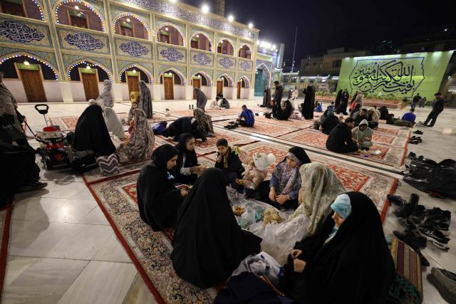 Iranian families break the dawn to dusk Ramadan fast during Iftar, in the grounds of the Imamzadeh Saleh mosque in Tehran on February 21, 2026. Muslims throughout the world are marking the month of Ramadan, the holiest month in the Islamic calendar, during which devotees fast from dawn until dusk. (Photo by ATTA KENARE / AFP)