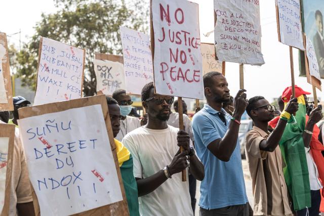 Students and activists hold placards during a demonstration demanding an end to police blunders and bring justice to the victims in Dakar on February 21, 2026. Students and pupils organizations, as well as activists, marched in Dakar on Saturday to “demand an end to police blunders and bring justice to the victims,” following the death of a student during a police operation at a university in the capital in early February. Abdoulaye Ba, a second-year medical student, died on February 9 on the campus of Cheikh Anta Diop University (UCAD) during a police operation, after several days of demonstrations and clashes between police and students protesting a reform of scholarship payments and demanding the settlement of arrears. (Photo by PATRICK MEINHARDT / AFP)