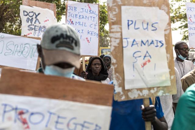 TOPSHOT - Students and activists hold placards during a demonstration demanding an end to police blunders and bring justice to the victims in Dakar on February 21, 2026. Students and pupils organizations, as well as activists, marched in Dakar on Saturday to “demand an end to police blunders and bring justice to the victims,” following the death of a student during a police operation at a university in the capital in early February. Abdoulaye Ba, a second-year medical student, died on February 9 on the campus of Cheikh Anta Diop University (UCAD) during a police operation, after several days of demonstrations and clashes between police and students protesting a reform of scholarship payments and demanding the settlement of arrears. (Photo by PATRICK MEINHARDT / AFP)