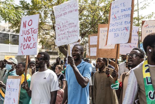 Students and activists hold placards and chant slogans during a demonstration demanding an end to police blunders and bring justice to the victims in Dakar on February 21, 2026. Students and pupils organizations, as well as activists, marched in Dakar on Saturday to “demand an end to police blunders and bring justice to the victims,” following the death of a student during a police operation at a university in the capital in early February. Abdoulaye Ba, a second-year medical student, died on February 9 on the campus of Cheikh Anta Diop University (UCAD) during a police operation, after several days of demonstrations and clashes between police and students protesting a reform of scholarship payments and demanding the settlement of arrears. (Photo by PATRICK MEINHARDT / AFP)