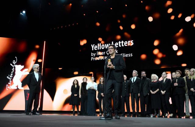 German film director ?lker Catak (C) holds the Golden Bear for Best Film he was given from Berlinale Jury President and German director Wim Wenders (L) for his movie "Gelbe Briefe (Yellow Letters)" during the Award Ceremony of the 76th Berlinale, Europe's first major film festival of the year, in Berlin on February 21, 2026. The 76th Berlin Film Festival draws to a close after 10 days, with 22 films in competition. (Photo by RALF HIRSCHBERGER / AFP)