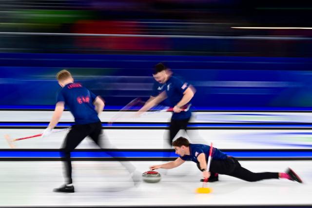 Britain's Grant Hardie (R) throws a stone flanked by Britain's Bobby Lammie (L) and Britain's Hammy Mcmillan (C) during the curling men's gold medal game between Great Britain and Canada during the Milano Cortina 2026 Winter Olympic Games at the Cortina Curling Olympic Stadium in Cortina d’Ampezzo on February 21, 2026. (Photo by Marco BERTORELLO / AFP)
