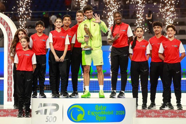 Spain's Carlos Alcaraz celebrates with the trophy after winning his men’s singles final match against France's Arthur Fils at the Qatar Open tennis tournament in Doha on February 21, 2026. (Photo by Karim JAAFAR / AFP)