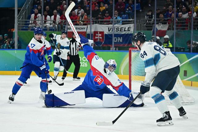 Slovakia's #31 Samuel Hlavaj (C) attempts to block a shot next to Finland's #84 Kaapo Kakko during the men's bronze medal ice hockey match between Slovakia and Finland at the Milano Santagiulia Ice Hockey Arena during the Milano Cortina 2026 Winter Olympic Games in Milan, on February 21, 2026. (Photo by JULIEN DE ROSA / AFP)