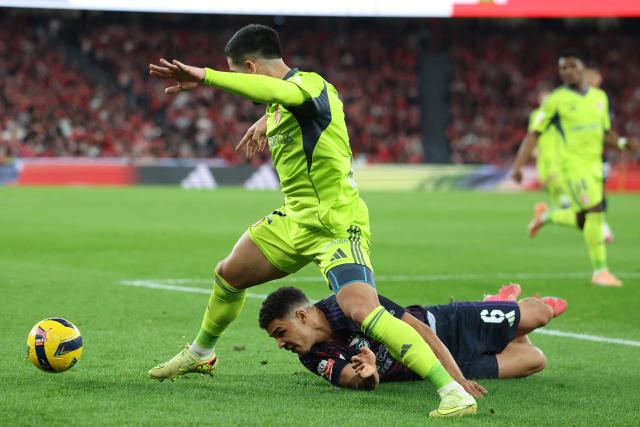AVS' Paraguayan defender #12 Daniel Rivas and SL Benfica's Danish defender #06 Alexander Bah fight for the ball during the Portuguese League football match between SL Benfica and AVS Futebol SAD at Estadio da Luz in Lisbon on February 21, 2026. (Photo by PATRICIA DE MELO MOREIRA / AFP)