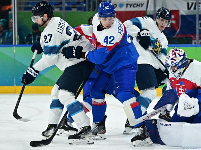 Finland's #27 Eetu Luostarinen, Slovakia's #42 Martin Fehervary, Finland's #15 Anton Lundell and Slovakia's #31 Samuel Hlavaj fight for the puck during the men's bronze medal ice hockey match between Slovakia and Finland at the Milano Santagiulia Ice Hockey Arena during the Milano Cortina 2026 Winter Olympic Games in Milan, on February 21, 2026. (Photo by JULIEN DE ROSA / AFP)