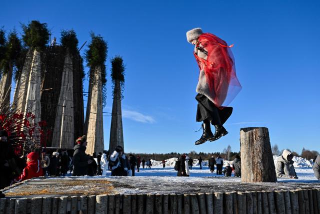 A woman jumps during celebrations of "Maslenitsa", the eastern Slavic Shrovetide in the village of Nikola-Lenivets,Kaluga region, some 220 km (140 miles) outside Moscow, on February 21, 2026, before the burning of a wooden structure called "Burning Heart" created by Russian artist Nikolay Polissky. Shrovetide or Maslenitsa is an ancient farewell ceremony to winter, traditionally celebrated in Belarus, Russia and Ukraine and involves the burning of a large effigy. (Photo by HECTOR RETAMAL / AFP)
