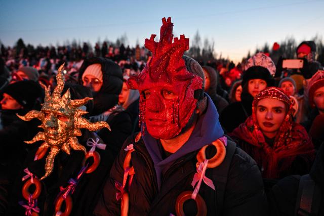 Spectators wearing costumes watch the burning of the 'Burning Heart", a wooden structure created by Russian artist Nikolay Polissky, during celebrations of "Maslenitsa", the eastern Slavic Shrovetide in the village of Nikola-Lenivets, Kaluga region, some 220 km (140 miles) outside Moscow, on February 21, 2026. Shrovetide or Maslenitsa is an ancient farewell ceremony to winter, traditionally celebrated in Belarus, Russia and Ukraine and involves the burning of a large effigy. (Photo by HECTOR RETAMAL / AFP)