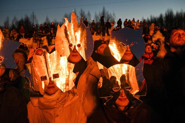 TOPSHOT - Spectators wearing costumes watch the burning of the 'Burning Heart", a wooden structure created by Russian artist Nikolay Polissky, during celebrations of "Maslenitsa", the eastern Slavic Shrovetide in the village of Nikola-Lenivets, Kaluga region, some 220 km (140 miles) outside Moscow, on February 21, 2026. Shrovetide or Maslenitsa is an ancient farewell ceremony to winter, traditionally celebrated in Belarus, Russia and Ukraine and involves the burning of a large effigy. (Photo by HECTOR RETAMAL / AFP)