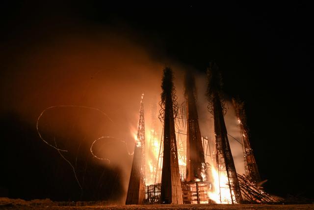 Spectators watch the burning of the 'Burning Heart", a wooden structure created by Russian artist Nikolay Polissky, during celebrations of "Maslenitsa", the eastern Slavic Shrovetide in the village of Nikola-Lenivets, Kaluga region, some 220 km (140 miles) outside Moscow, on February 21, 2026. Shrovetide or Maslenitsa is an ancient farewell ceremony to winter, traditionally celebrated in Belarus, Russia and Ukraine and involves the burning of a large effigy. (Photo by HECTOR RETAMAL / AFP)
