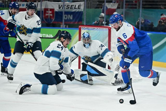 Finland's #24 Roope Hintz, Finland's #74 Juuse Saros and Slovakia's #06 Lukas Cingel fight for the puck during the men's bronze medal ice hockey match between Slovakia and Finland at the Milano Santagiulia Ice Hockey Arena during the Milano Cortina 2026 Winter Olympic Games in Milan, on February 21, 2026. (Photo by JULIEN DE ROSA / AFP)