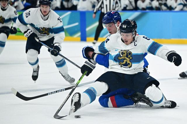 Slovakia's #20 Juraj Slafkovsky and Finland's #64 Mikael Granlund fight for the puck during the men's bronze medal ice hockey match between Slovakia and Finland at the Milano Santagiulia Ice Hockey Arena during the Milano Cortina 2026 Winter Olympic Games in Milan, on February 21, 2026. (Photo by JULIEN DE ROSA / AFP)