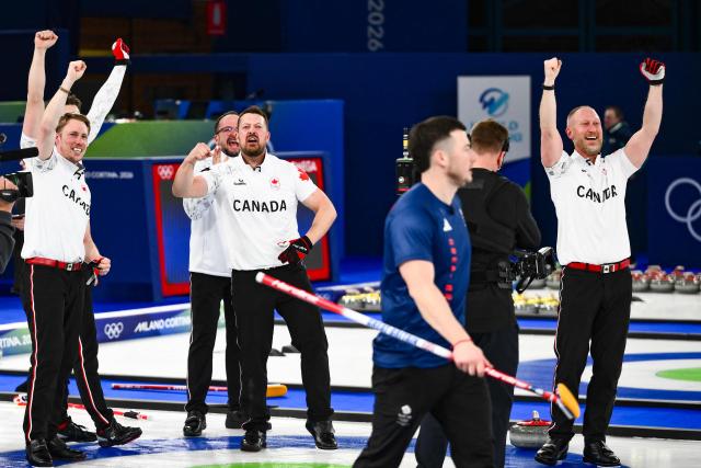 Canada's Marc Kennedy (L) Canada's Ben Hebert (C) and Canada's Brad Jacobs celebrate becoming Olympic Champions as Britain's Hammy Mcmillan walks off after defeating team GB in the curling men's gold medal game between Great Britain and Canada during the Milano Cortina 2026 Winter Olympic Games at the Cortina Curling Olympic Stadium in Cortina d’Ampezzo on February 21, 2026. (Photo by Marco BERTORELLO / AFP)