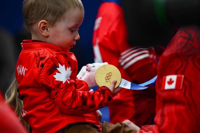 2 1/2 year old Luke, son of Canada's Brett Gallant holds his fathers gold medal after team Canada defeated team GB in curling at the Milano Cortina 2026 Winter Olympic Games at the Cortina Curling Olympic Stadium in Cortina d’Ampezzo on February 21, 2026. (Photo by Marco BERTORELLO / AFP)