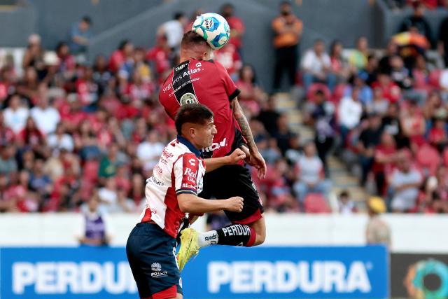 Atlas' Brazilian forward #03 Gustavo Ferrareis heads the ball past San Luis' midfielder #07 Benjamin Galdames during the Liga MX Clausura football match between Atlas and San Luis at the Jalisco Stadium in Guadalajara, state of Jalisco, Mexico, on February 21, 2026. (Photo by Ulises Ruiz / AFP)