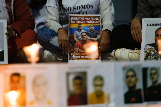 People show signs during a vigil to demand the freedom of political prisoners outside the El Helicoide building, headquarters of the Bolivarian National Intelligence Service (SEBIN), in Caracas on February 21, 2026. Venezuelan authorities granted amnesty to 379 political prisoners on February 20, 2026 after a new mass amnesty law was enacted following the ouster of former leader Nicolas Maduro. (Photo by Pedro MATTEY / AFP)