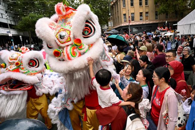 People interact with lion dancers during celebrations marking the Lunar New Year of the Horse in Melbourne on February 22, 2026. (Photo by William WEST / AFP)