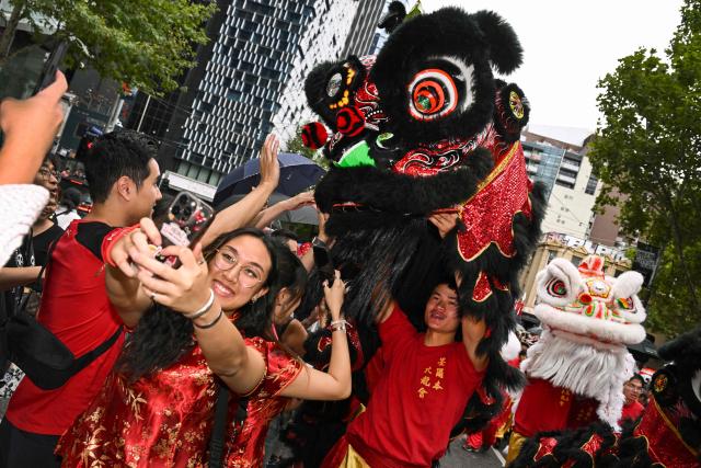 People interact with lion dancers during celebrations marking the Lunar New Year of the Horse in Melbourne on February 22, 2026. (Photo by William WEST / AFP)