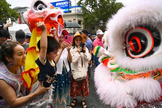 People interact with lion dancers during celebrations marking the Lunar New Year of the Horse in Melbourne on February 22, 2026. (Photo by William WEST / AFP)