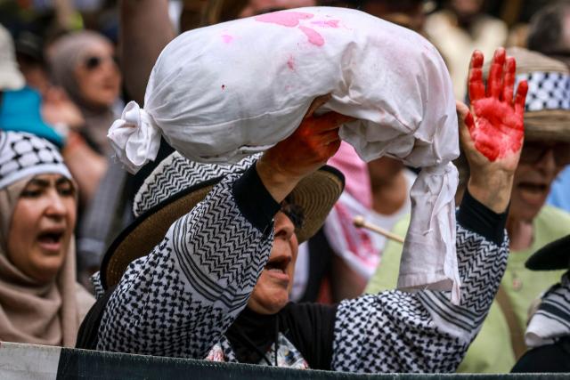 A pro-Palestinian demonstrator with her hands painted red chants slogans as she marches through the streets during a rally in Sydney on February 22, 2026. (Photo by DAVID GRAY / AFP)