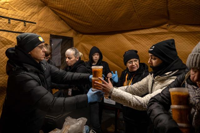 Volunteers distribute hot meal to local residents in a heated tent in Odesa on February 18, 2026, amid the Russian invasion of Ukraine. (Photo by Oleksandr GIMANOV / AFP)