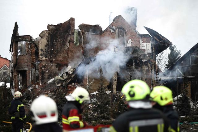 Ukrainian rescuers stand next to a heavily damaged house following an air attack in Sofiivska Borshchagivka, Kyiv region on February 22, 2026, amid the Russian invasion of Ukraine. Explosions rocked Ukraine's capital Kyiv with officials warning of a ballistic missile attack, just two days before the fourth anniversary of Russia's invasion. (Photo by Henry NICHOLLS / AFP)