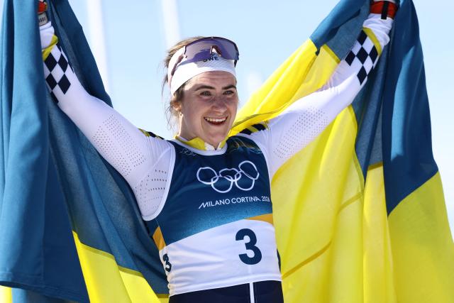 Sweden's Ebba Andersson celebrates with a flag of Sweden after crossing the finish line to win the women's cross country 50km mass start final event of the Milano Cortina 2026 Winter Olympic Games at Tesero Cross-Country Skiing Stadium in Lago di Tesero (Val di Fiemme), on February 22, 2026. (Photo by Anne-Christine POUJOULAT / AFP)