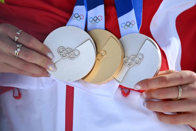 Gold medallist China's Gu Ailing Eileen celebrates on the podium with her three olympic medals (two silver and one gold medal) after winning the freestyle skiing women's freeski halfpipe final during the Milano Cortina 2026 Winter Olympic Games at Livigno Snow Park, in Livigno (Valtellina), on February 22, 2026. (Photo by Kirill KUDRYAVTSEV / AFP)