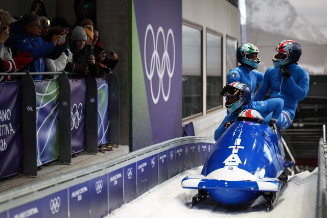 Italy's Patrick Baumgartner, Italy's Lorenzo Bilotti, Italy's Eric Fantazzini and Italy's Robert Mircea react after crossing the finish line in the bobsleigh men's 4-man heat 4 at Cortina Sliding Centre during the Milano Cortina 2026 Winter Olympic Games in Cortina d'Ampezzo on February 22, 2026. (Photo by FRANCK FIFE / AFP)