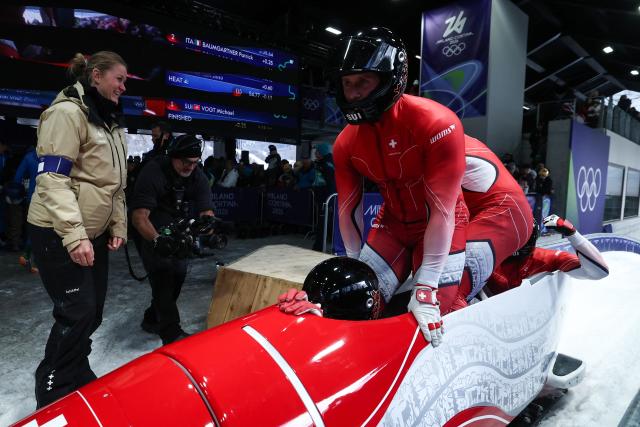 Switzerland's Michael Vogt, Switzerland's Andreas Haas, Switzerland's Amadou David Ndiaye and Switzerland's Mario Aeberhard react after crossing the finish line in the bobsleigh men's 4-man heat 4 at Cortina Sliding Centre during the Milano Cortina 2026 Winter Olympic Games in Cortina d'Ampezzo on February 22, 2026. (Photo by FRANCK FIFE / AFP)