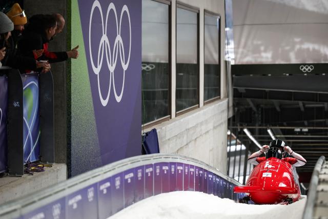 Switzerland's Michael Vogt, Switzerland's Andreas Haas, Switzerland's Amadou David Ndiaye and Switzerland's Mario Aeberhard react after crossing the finish line in the bobsleigh men's 4-man heat 4 at Cortina Sliding Centre during the Milano Cortina 2026 Winter Olympic Games in Cortina d'Ampezzo on February 22, 2026. (Photo by FRANCK FIFE / AFP)