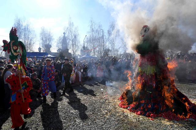People watch a burning straw-wood-and-cloth effigy representing Mother Winter as they celebrate Maslenitsa (Shrovetide), a farewell ceremony to winter, in the village of Leninskoye on February 22, 2026. Shrovetide precedes the beginning of Lent, with each day of the week holding its own meaning. Shrove Sunday, also known as the Sunday of Forgiveness, is a day for asking forgiveness for the harm caused to other people intentionally or unintentionally. (Photo by Vyacheslav OSELEDKO / AFP)
