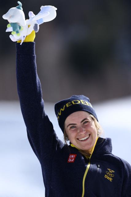 Gold medallist Sweden's Ebba Andersson celebrates on the podium the women's cross country 50km mass start final event of the Milano Cortina 2026 Winter Olympic Games at Tesero Cross-Country Skiing Stadium in Lago di Tesero (Val di Fiemme), on February 22, 2026. (Photo by Anne-Christine POUJOULAT / AFP)