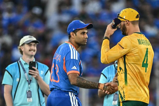 India's captain Suryakumar Yadav (C) and his South African counterpart Aiden Markram (R) shake hands during the toss before the start of the 2026 ICC Men's T20 Cricket World Cup Super Eights match between India and South Africa at the Narendra Modi Stadium in Ahmedabad on February 22, 2026. (Photo by Manan VATSYAYANA / AFP)