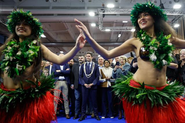 President of Ensemble Pour la Republique parliamentary group Gabriel Attal (C) accompanied by Ensemble Pour la Republique's MP Jean-Luc Fugit (C-L) attend the performance of dancers  at the Tahiti stall as he visits the International Agricultural Show (Salon de l'Agriculture) at Paris Expo Porte de Versailles in Paris on February 22, 2026. (Photo by Charlotte SIEMON / AFP)