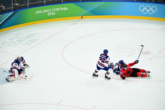 USA's #37 Connor Hellebuyck (L) defends as Canada's #29 Nathan MacKinnon (R) falls  during the men's gold medal ice hockey match between Canada and USA at the Milano Santagiulia Ice Hockey Arena during the Milano Cortina 2026 Winter Olympic Games in Milan, on February 22, 2026. (Photo by JULIEN DE ROSA / AFP)